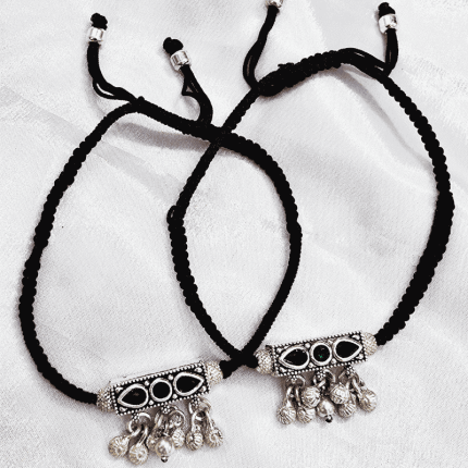 Traditional braided anklets featuring oxidized cylindrical pendants and hanging bells.